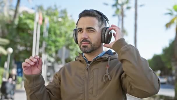 Handsome Hispanic Man Beard Wearing Headphones Enjoys Music Sunny Urban — Stock Video