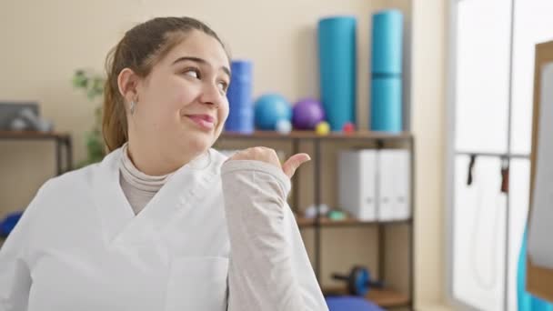 Jovem Hispânica Alegre Uniforme Enfermeira Apontando Para Cima Sorrindo Brilhantemente — Vídeo de Stock