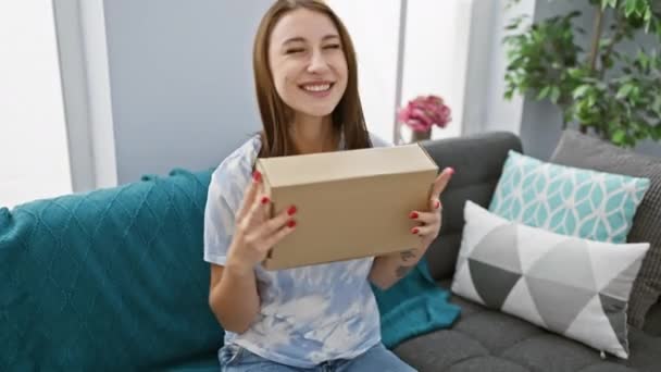 Joyful Woman Home Opening Cardboard Box While Sitting Grey Sofa — Stock Video