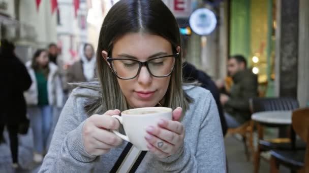 在街道背景模糊的室外咖啡馆喝咖啡的年轻女子 — 图库视频影像