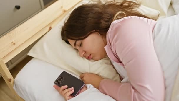 Pokojowa Latynoska Kobieta Śpi Łóżku Trzymając Smartfona Jasnym Wnętrzu Sypialni — Wideo stockowe