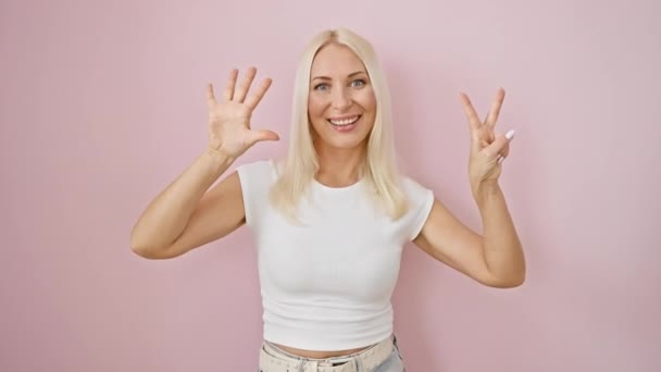 Радостная Молодая Блондинка Уверенно Указывает Номер Семь Пальцами Излучая Счастье — стоковое видео