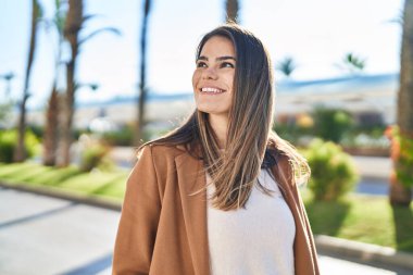 Young beautiful hispanic woman smiling confident looking to the sky at street