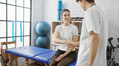 Fizyoterapist, tedavi sürecini gösteren bir fizyoterapi kliniğinde hasta bir kadına yardım eder..