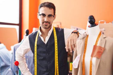 Genç İspanyol terzi gülümsüyor Atölyede kendine güvenen manikine yaslanıyor