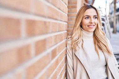 Young blonde woman smiling confident looking to the side at street