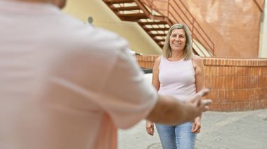 Kendine güvenen anne ve oğul, gülümseyen ve birbirlerine bakan, günlük şehir tarzında güneşli sokak hayatının tadını çıkaran, neşe, sevgi, aile bağı ve açık hava yaşam tarzının özünü mükemmel bir şekilde yakalayan..