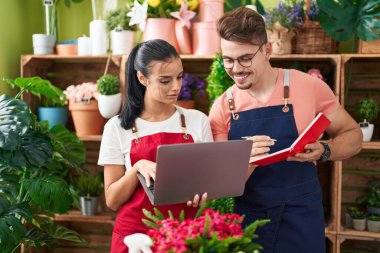 Çiçekçide dizüstü bilgisayar kullanan erkek ve kadın çiçekçiler.