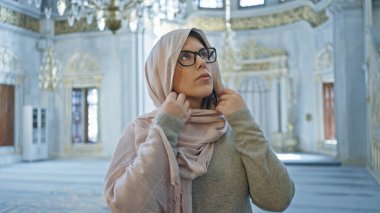 Düşünceli bir kadın, karmaşık İslami mimarisi olan geniş bir camide tesettüre ayak uyduruyor.