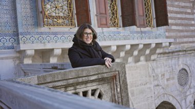 Gülen kadın gözlüklü, Topkapı Sarayı 'nın balkonuna yaslanmış, İstanbul' da Osmanlı mimarisi sergiliyor, hindi....