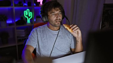 Geceleri karanlık bir odada oyun oynarken sakallı İspanyol bir adam yemek yiyor..