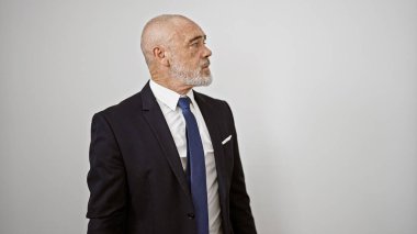 Takım elbiseli, kendinden emin orta yaşlı bir adam beyaz bir arka plana karşı poz veriyor..