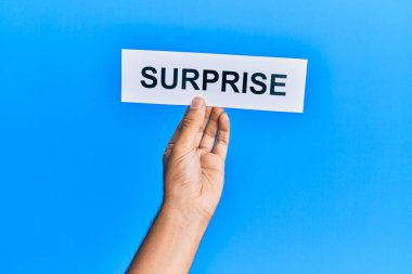 Kafkasyalı bir adamın elinde, mavi arka planda sürpriz sözcüklerle dolu bir kağıt var.