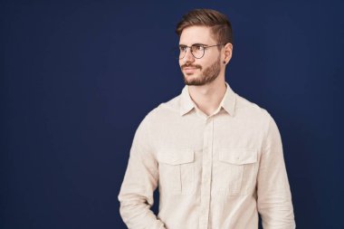 Mavi arka planda sakallı İspanyol bir adam gülümsüyor ve yan tarafa bakıyor.. 