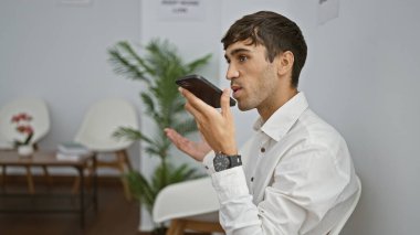 Ciddi, genç İspanyol bir adam iş yapmak istiyor. Bekleme odasında güvenle oturuyor. Akıllı telefonuyla tutkuyla sesli mesaj gönderiyor.