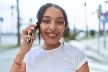 Young arab woman smiling confident using smartphone at street