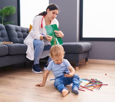 Anne ve oğul doktor evdeki çocuğu muayene eden belgeye yazıyor.