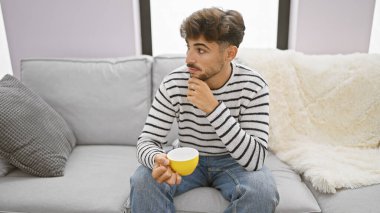 Rahatlatıcı bir sabah, sakallı yakışıklı Arap bir adam, evdeki kanepesinde rahatça dinleniyor, bir fincan espressonun keyfini çıkarıyor, sessiz, kahve içmenin basit zevkini yaşıyor.