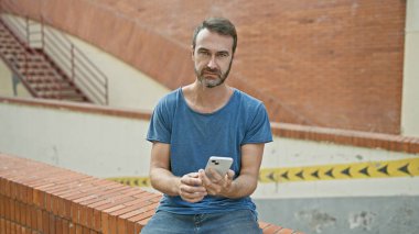 Sakallı yakışıklı İspanyol adam. Şehir caddesinde akıllı telefon kullanıyor.