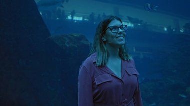 Gülümseyen genç bir kadın, Dubai 'de bir akvaryumun manzarasının keyfini çıkarıyor. Deniz yaşamı camdan görülebiliyor..