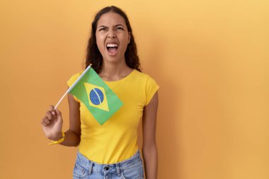 Elinde Brezilya bayrağı tutan genç İspanyol kadın kızgın ve kızgın bağırıyor sinirli ve öfkeli, öfkeyle bağırıyor. öfke ve agresif konsept. 