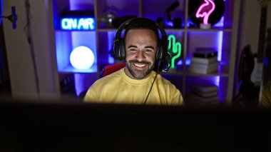 İyi ışıklandırılmış bir odada oyun masasında gülümseyen sakallı yakışıklı İspanyol bir adam..