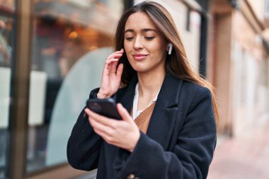 Genç, güzel, İspanyol bir kadın sokakta müzik dinliyor.