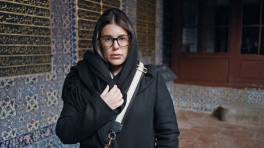 Siyah paltolu düşünceli bir kadın İstanbul 'da döşeli bir duvarın önünde duruyor..