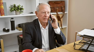 Olgun, ciddi yüzlü bir kıdemli adam önemli bir iş konuşmasına dalmış, acımasız bir işçi, ofisinde otururken akıllı telefonuna sesleniyor, profesyonel zarafet yayıyor..