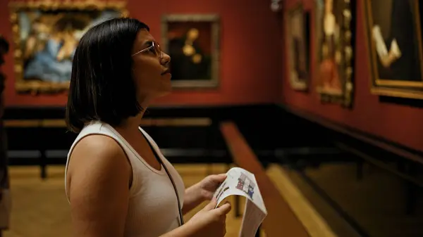 在维也纳艺术博物馆参观美术馆的年轻美丽的惊慌失措的女人阅读小册子 — 图库照片