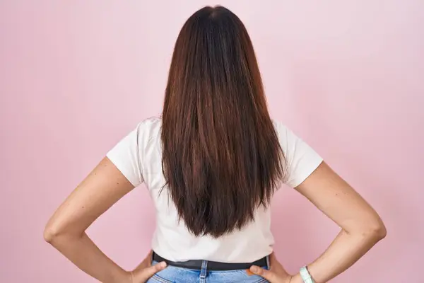 Young Brunette Woman Standing Pink Background Standing Backwards Looking Away — Stok fotoğraf