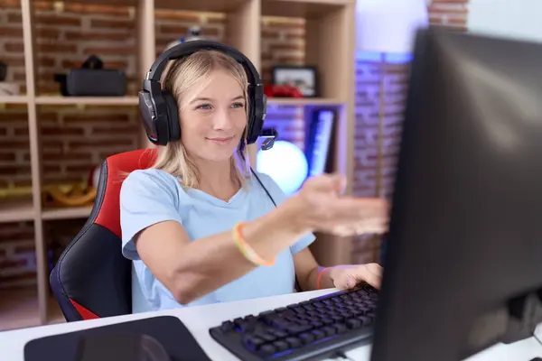 若い慎重な女性はヘッドフォンを着用してビデオゲームをプレイし 陽気な提供ヤシの手助けと受諾を与える — ストック写真