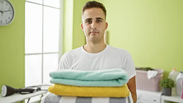 Young Man Standing Laundry Room Holding Folded Clothes Washing Machine — Stock Photo, Image