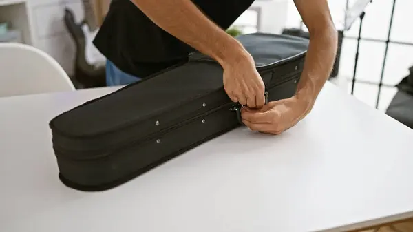 Talented hispanic male musician\'s hands captured opening acoustic violin case for intense practice session inside buzzing music studio