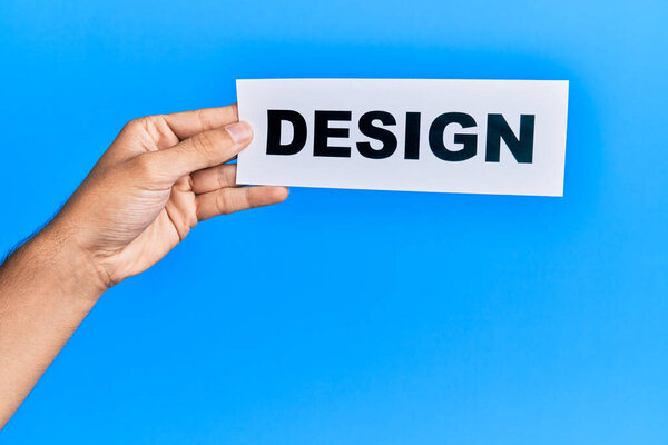 Hand of caucasian man holding paper with design word over isolated blue background