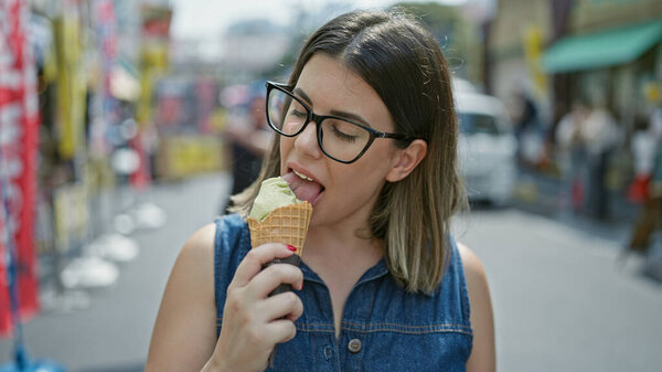 Cheerful and beautiful hispanic woman in glasses happily savors a delicious ice cream cone amidst the bustling tsukiji outer market - tokyo summer fun!