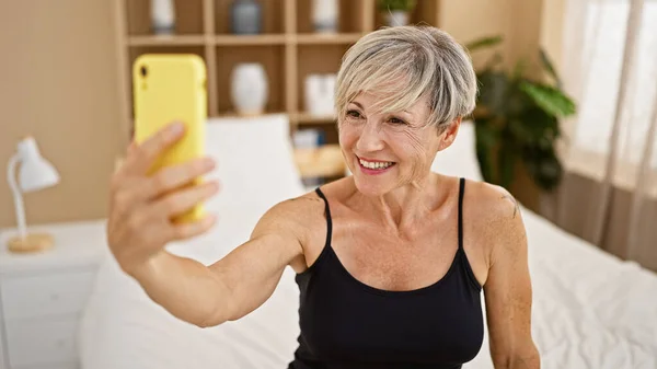 Cheerful Mature Woman Takes Selfie Bright Bedroom Embodying Positivity Modern — Stock Photo, Image