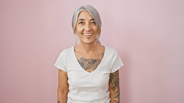 Neşeyle parıldayan, beyaz saçlı, kendine güvenle köpüren, modern, izole pembe bir arka plana karşı sıradan bir şekilde duran göz alıcı orta yaşlı kadın. Kesinlikle sahipleniyorum.!