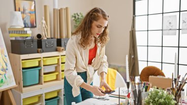 Çekici genç kadın sanatçı, kapalı alanda resim çizmek için güzel sanatların resimlerini çekiyor.