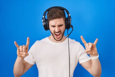 Sakallı, müzik dinleyen, kulaklık takan çılgın bir ifadeyle bağıran, elleri havada rock sembolü yapan İspanyol bir adam. Müzik yıldızı. ağır müzik konsepti. 