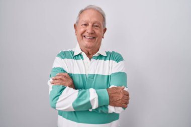 Beyaz arka planda gri saçlı yaşlı adam kollarını kavuşturup kameraya bakarken gülümsüyor. pozitif kişi. 