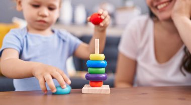 Anne ve oğlu evde oynarken kendinden emin gülümsüyor.