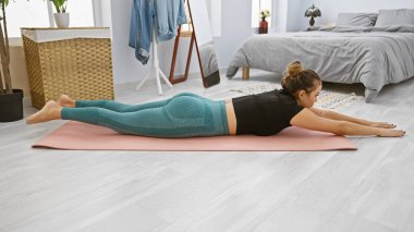 Genç, güzel İspanyol kadın yatak odasında bel egzersizi yapıyor.