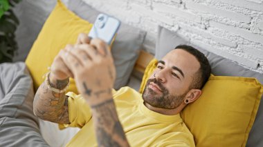 Sakallı, sakallı, evde telefonunu kullanarak ev hayatını somutlaştıran gevşemiş bir İspanyol..