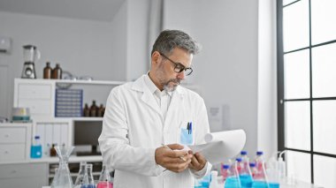 Yakışıklı, gri saçlı İspanyol bilim adamı. Dosyada tıbbi raporları okumaya dalmış. Laboratuvarda özenle çalışıyor.!