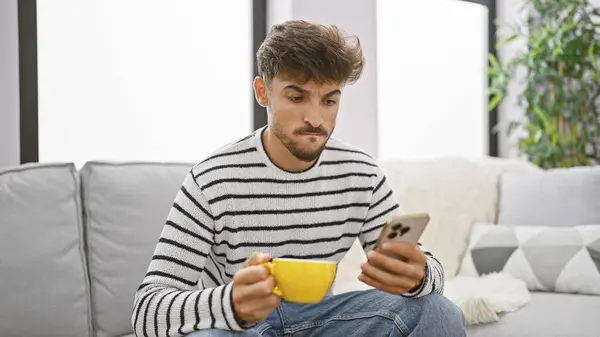 Hombre Árabe Joven Guapo Relajándose Casa Bebiendo Café Usando Teléfono — Foto de Stock
