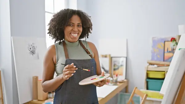 Smiling black woman with braids painting in an art studio
