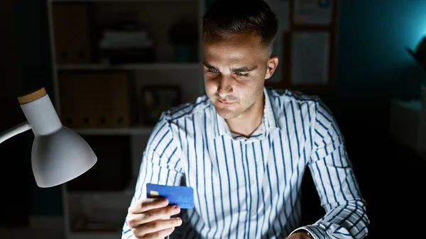 Young Hispanic Man Holding Credit Card Well Lit Office Minimalistic — Stock Photo, Image