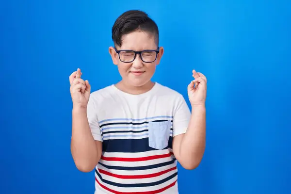 Joven Niño Hispano Pie Sobre Fondo Azul Gesto Dedo Cruzado —  Fotos de Stock