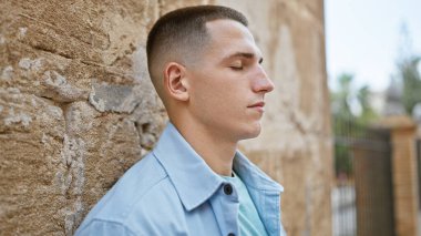 Yakışıklı İspanyol bir adam, sakin bir anda, eski bir şehir duvarına yaslanıyor..